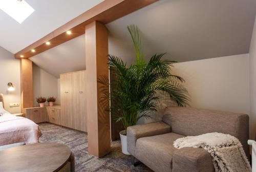 a bedroom with a bed and a chair and a plant at Old Town Trio Apartments in Vilnius