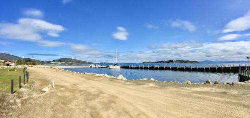 a dirt road next to a body of water with boats at Manfield Seaside Bruny Island in Alonnah
