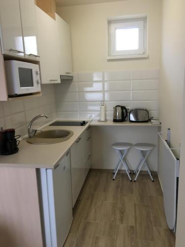 a kitchen with a sink and two stools in it at Kristály apartmanok in Kisvárda