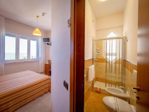 a bathroom with a bed and a shower and a sink at Hotel de la Ville in Senigallia