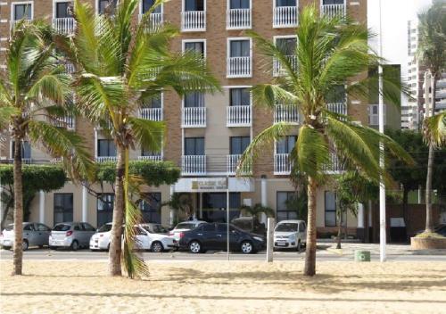 a row of palm trees in front of a building at Hotel Flat Classic in Fortaleza