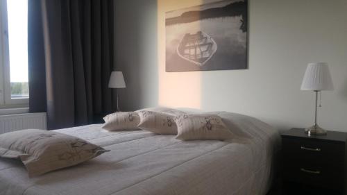 una camera da letto con letto, lenzuola e cuscini bianchi di Pähkinäpuisto Apartments a Tampere