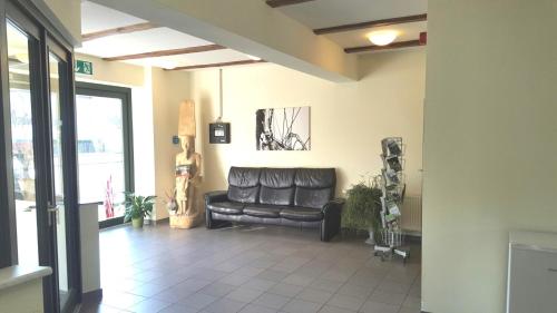 a living room with a black leather couch in a room at Radlerhof Spreewald in Kolkwitz