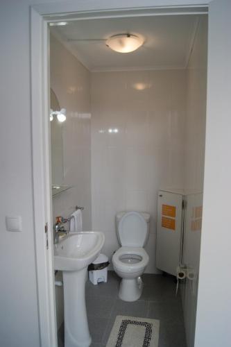 a white bathroom with a toilet and a sink at Azores Dream Hostel in Ponta Delgada