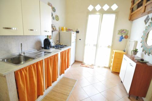 a kitchen with an orange curtain on the counters at Case Vacanze Agrumi in Portopalo
