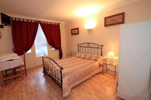 1 dormitorio con cama, escritorio y cortinas rojas en Au Bon Laboureur, en Bray-sur-Seine