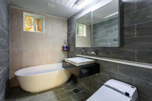 Un baño con bañera, lavabo e inodoro. en Mar En Luz, en Seogwipo