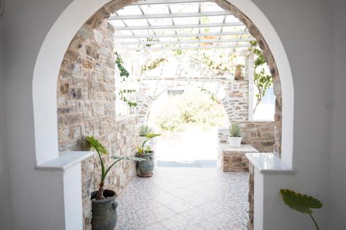 an arched hallway with potted plants and a brick wall at Asteras in Antiparos Town