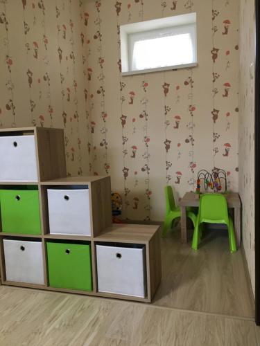 a childs room with green and white drawers and a table at Kristály apartmanok in Kisvárda