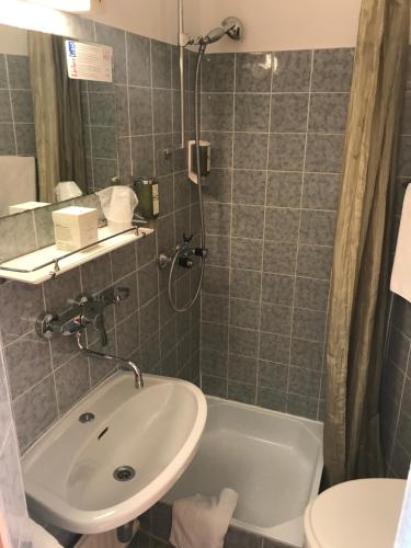 a bathroom with a sink and a tub and a toilet at Boutiquehotel Stefanie in Bad Vöslau
