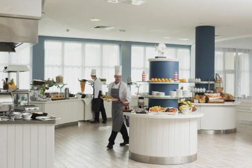 two chefs standing in a kitchen with a plate of food at Precise Resort Hafendorf Rheinsberg in Rheinsberg