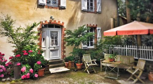 a house with a porch with chairs and flowers at Relais de Chasse la Chaignaie in Montaigu-Vendée
