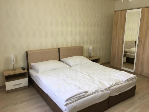 a bedroom with a bed with white sheets and a mirror at Kristály apartmanok in Kisvárda