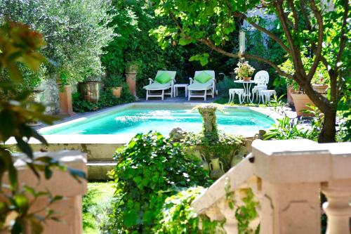 a backyard with a pool with chairs and a table at Les Saisons in Villeneuve-lès-Avignon