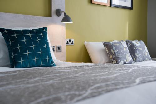 a bedroom with a bed with blue and white pillows at The Hedgehog by Innkeeper's Collection in Lichfield