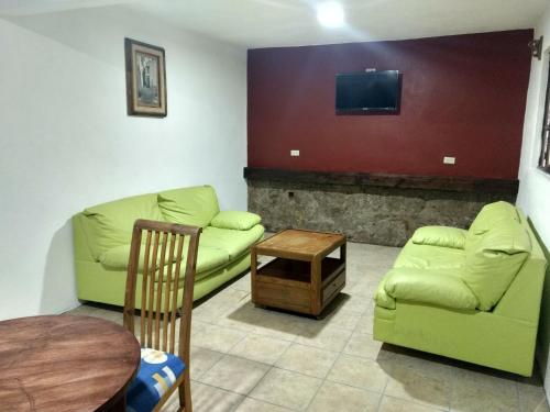 a living room with two green couches and a table at Hotel Hacienda Morales. in Guanajuato