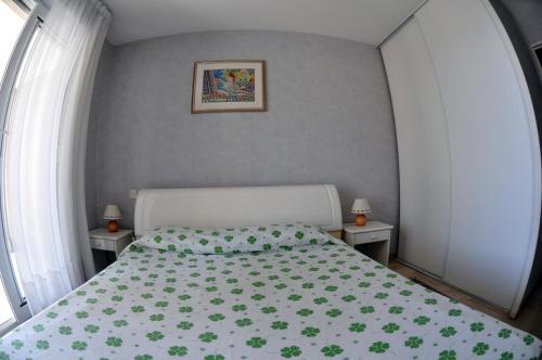 a bedroom with a bed with a green bedspread at Les Pins Bleus - Antibes Juan Les Pins in Juan-les-Pins