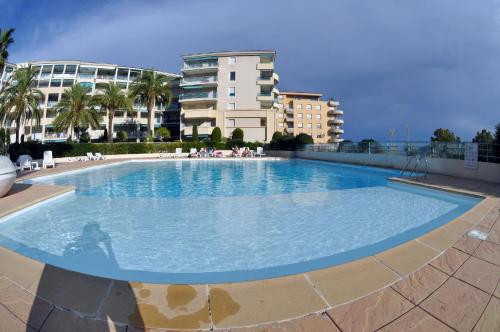 une grande piscine devant un immeuble dans l'établissement Les Pins Bleus - Antibes Juan Les Pins, à Juan-les-Pins
