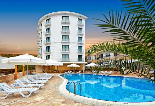 a hotel with a pool and chairs and a building at Ayvalik Cinar Hotel in Ayvalık