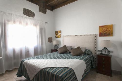 a bedroom with a bed with a striped blanket and a window at Caserío Leandro III in Mácher