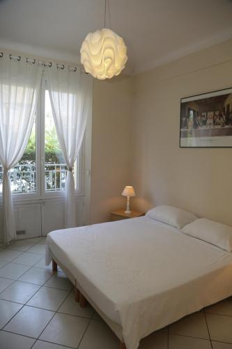 a bedroom with a large white bed and a chandelier at Plage du Midi in Cannes