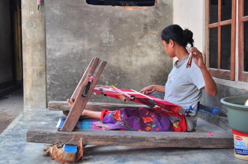 a woman sitting on a table with a chair at Mu Homestay in Tetebatu