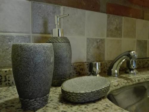 a bathroom counter with a sink and a soap dispenser at Alma Serrana Apart Cabañas - Solo Adultos in Nono