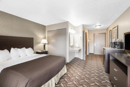 a hotel room with a large bed and a bathroom at Days Inn by Wyndham Bismarck in Bismarck