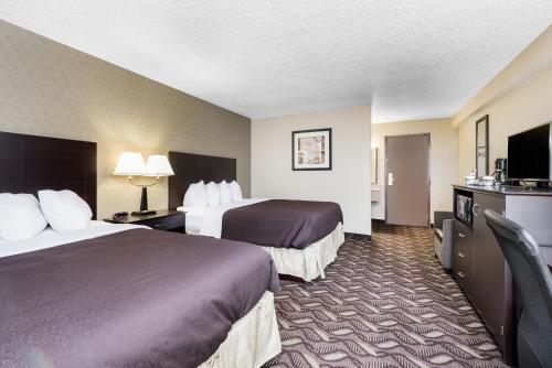 a hotel room with two beds and a flat screen tv at Days Inn by Wyndham Bismarck in Bismarck