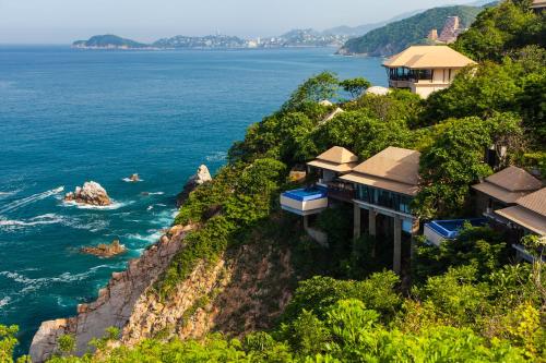 a house on a cliff next to the ocean at Banyan Tree Cabo Marques in Acapulco