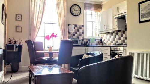 uma cozinha com cadeiras e uma mesa e um relógio na parede em Bailie Royal Mile Apartment em Edimburgo