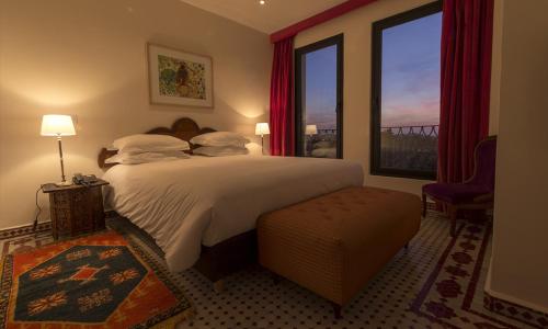 a bedroom with a large bed and a large window at Soundouss Hotel in Rabat