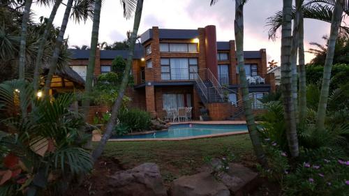 a house with a swimming pool and palm trees at Andre's Place in Durban