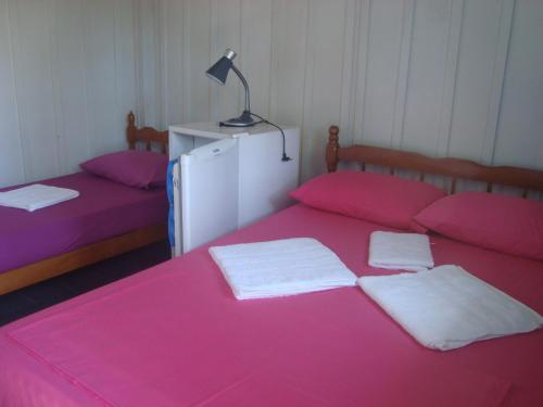 a bedroom with two beds with pink sheets and a lamp at Dona Quinota in Ilha do Mel