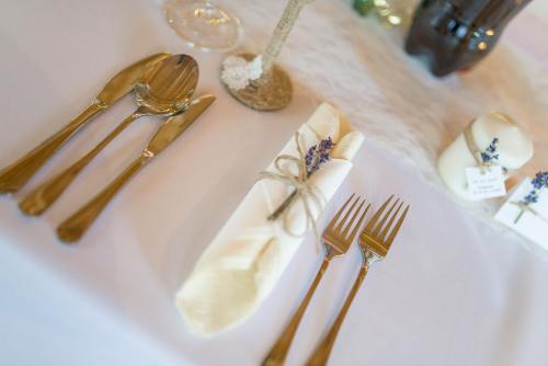 a white table with gold forks and napkins on it at Ranč pod Ostrou Skalou in Stratená
