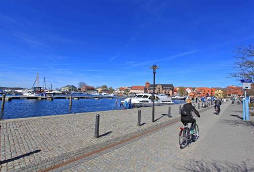 ヴァーレンにあるFerienwohnungen Waren SEE 9250の川沿いの歩道を自転車に乗る女