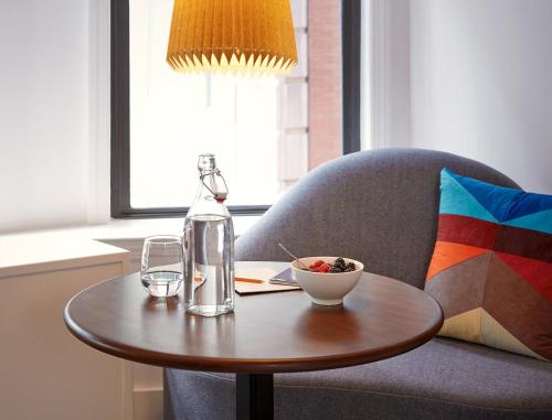 a table with a bottle and a bowl on a chair at Hotel Seville NoMad - The Unbound Collection by Hyatt in New York