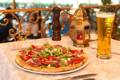 a pizza on a table with a glass of beer at Hotel Victoria in Lugano