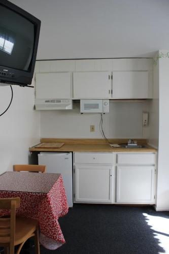 a kitchen with a table and a tv on a wall at Flagship Motorcourt in Hampton