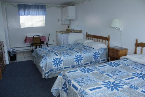 a bedroom with two beds with blue and white sheets at Flagship Motorcourt in Hampton