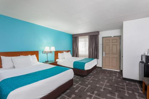 a hotel room with two beds and a television at Howard Johnson by Wyndham National City/San Diego South in National City