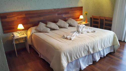 a bedroom with a large white bed with two lamps at Tres Pircas Hotel & Spa in Huerta Grande