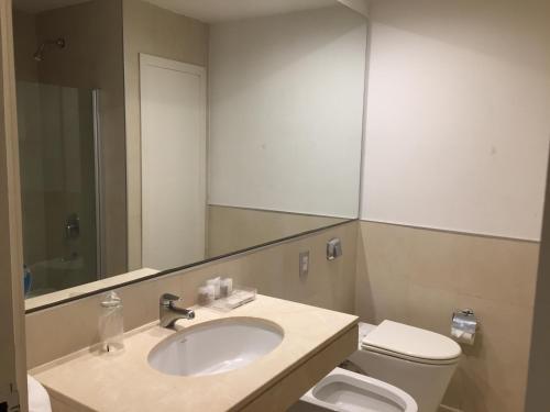 a bathroom with a sink and a toilet and a mirror at NH Gran Hotel Provincial in Mar del Plata