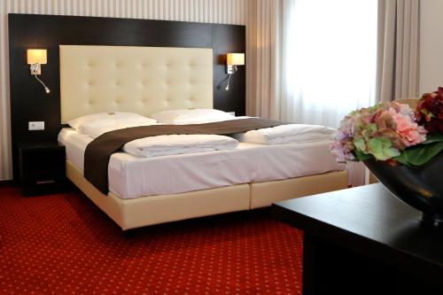 ベルリンにあるホテル ハーベスト ベルリンの赤いカーペット敷きの客室の大型ベッド1台分です。