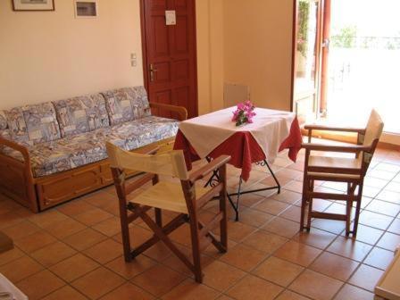 sala de estar con mesa, sillas y sofá en Hotel Heleni Apartments, en Palaia Epidavros