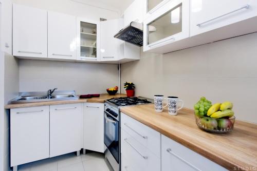 a kitchen with white cabinets and a wooden counter top at ClickTheFlat Avenue Place Apart Rooms in Warsaw