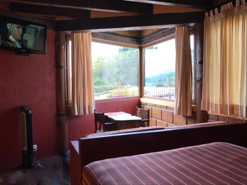 a bedroom with a bed and a large window at Hotel puesta del sol in Valle de Bravo