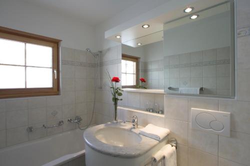 ein Badezimmer mit einem Waschbecken, einer Badewanne und einem Spiegel in der Unterkunft Hotel Allegra in Zuoz