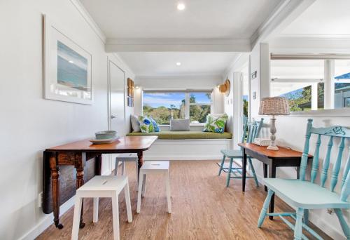 a dining room with a table and chairs and a couch at The Little Blue Bach in Oneroa Village by Waiheke Unlimited in Oneroa