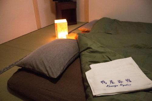 a pillow with a sign on it sitting on a bed at Kamoya Ryokan in Kyoto